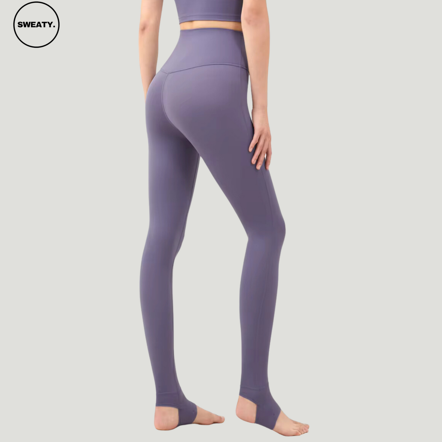 Back view of Amethyst Breathable Stirrup Yoga Leggings by SWEATY, highlighting the high-waisted fit and flattering rear contour design. The leggings include stirrup straps for added support and functionality, ideal for active movements during yoga or fitness sessions. The amethyst color provides a stylish look with optimal comfort.