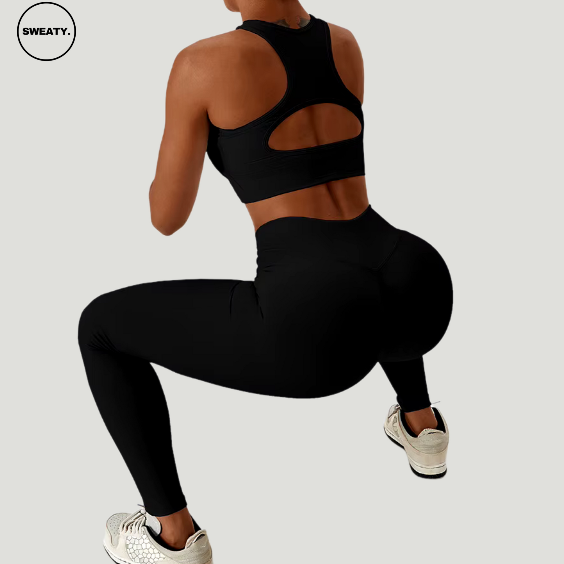 Black seamless sportswear set by SWEATY – back view in squat position, highlighting the supportive sports bra with cutout and high-waisted leggings. Ideal for fitness and gym routines, featuring breathable, flexible fabric.