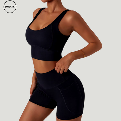 Side view of the black seamless tracksuit set by SWEATY. Women’s black activewear with quick-dry and breathable material, designed for fitness activities like yoga and running. Features high-waisted black shorts with side pockets and a supportive black sports bra.

