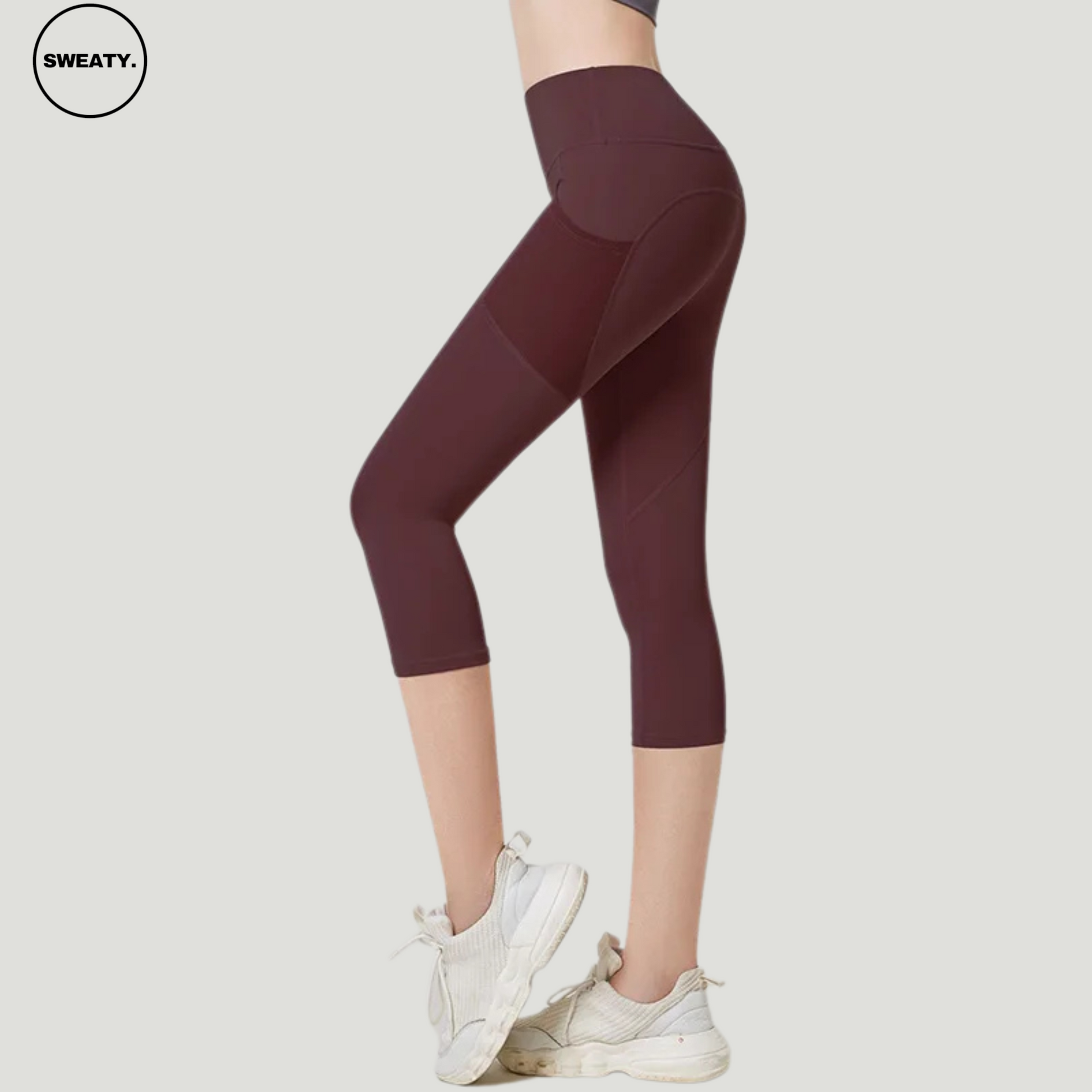 SWEATY Brown High Waist Capri Pants with Mesh Pockets. These stylish capri-length yoga pants feature a high-rise design with mesh detailing on the sides for enhanced breathability, making them ideal for fitness routines.