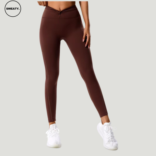 Front view of the Coffee Hips Yoga Legging by SWEATY, featuring a high-waist design with a flattering V-shaped waistline, perfect for yoga and fitness activities. Paired with white sneakers for a chic and comfortable workout look.