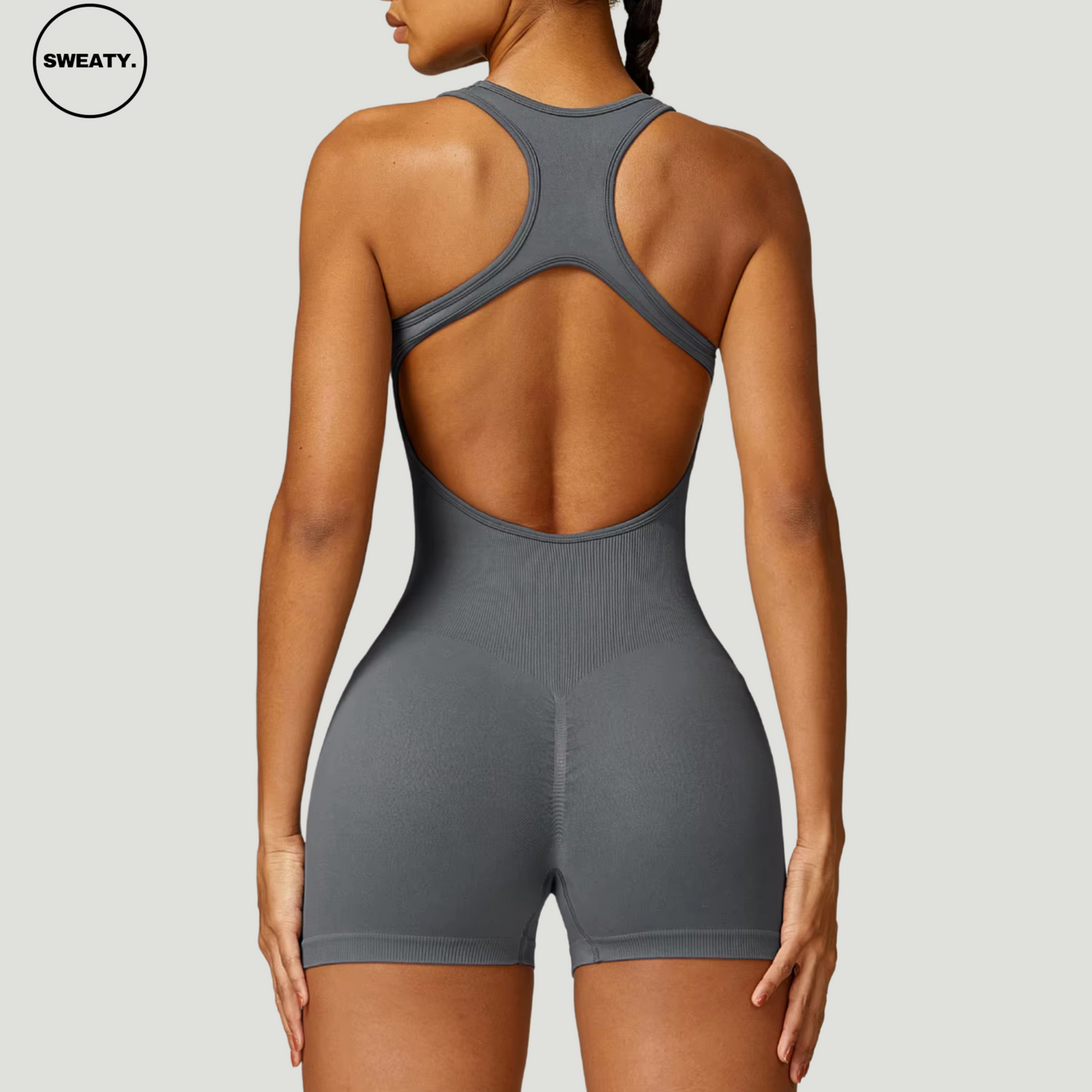 Grey seamless gym shortie jumpsuit by SWEATY - Women's close-up back view showing the racerback detail and snug, sculpting fit. This jumpsuit is ideal for fitness routines, offering a seamless, comfortable, and flexible design.