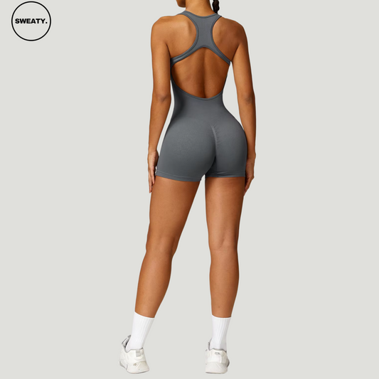 Grey seamless gym shortie jumpsuit by SWEATY - Women's full back view highlighting the open-back racerback design and high-performance fit. The seamless construction ensures flexibility and comfort during gym workouts or fitness activities.