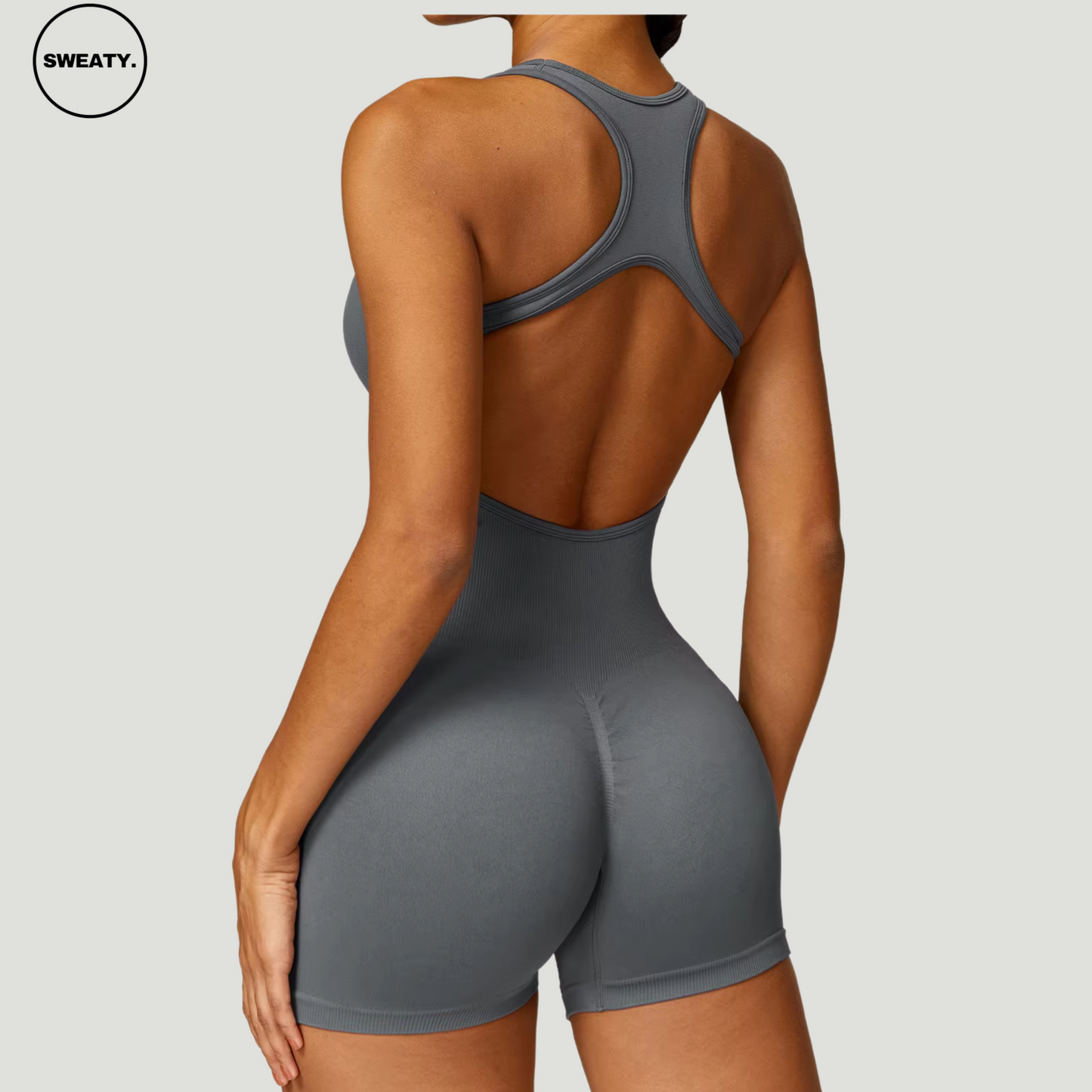 Grey seamless gym shortie jumpsuit by SWEATY - Women's side back view showcasing the racerback design and figure-hugging fit. Perfect for intense workouts, this jumpsuit offers breathable, seamless construction for maximum comfort.