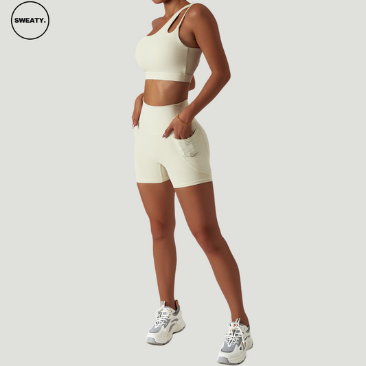 Ivory Scrunch Workout Two-Piece by SWEATY – Side view of the shorts set with a one-shoulder crop top and high-waisted shorts, designed for yoga, fitness, and running. Made from breathable, quick-drying fabric.