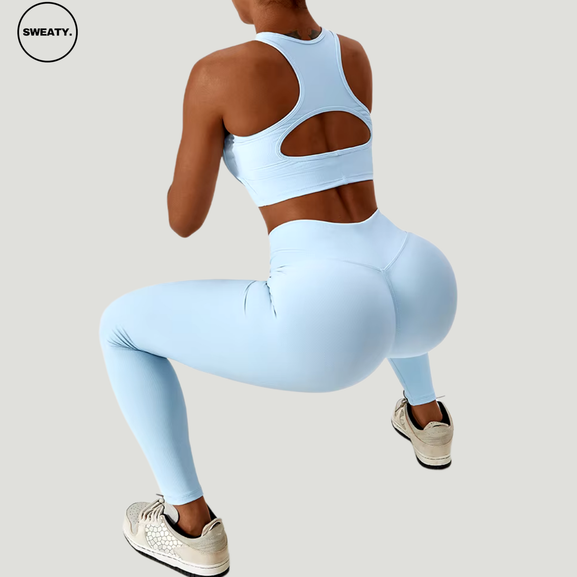 Sky Blue seamless sportswear set by SWEATY – back view in a squatting pose showcasing the racerback sports bra and high-waisted leggings. Designed with breathable, moisture-wicking fabric for comfort during intense workouts.