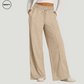 Front view of a woman wearing khaki wide-leg fleece-lined sweatpants, featuring an elastic drawstring waistband and side pockets. These relaxed-fit pants offer cozy wear for lounging or casual outings. Paired with a white long-sleeve crop top and white sneakers.