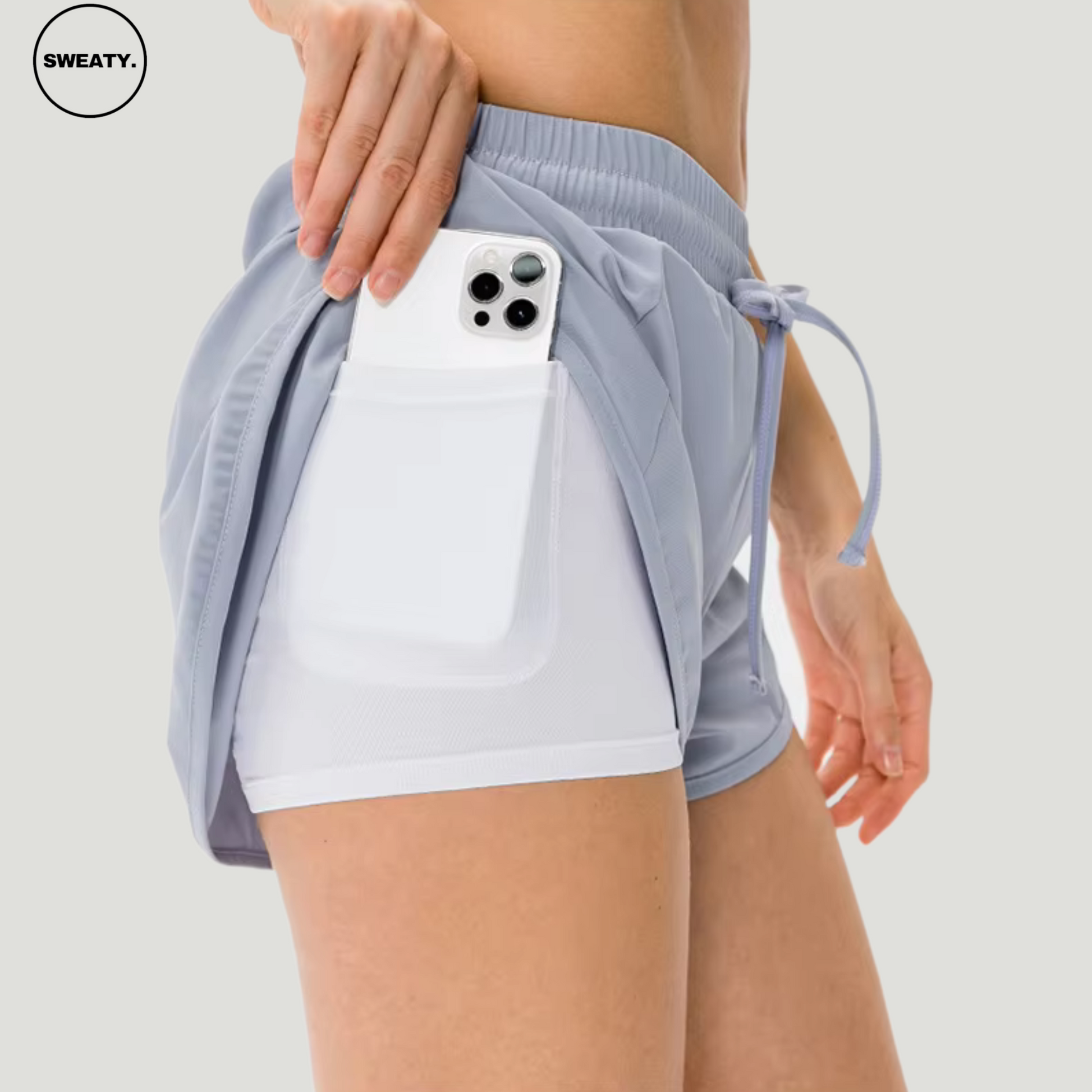 Close-up view of a woman wearing a light blue 2-in-1 skort from SWEATY, featuring an inner phone pocket and breathable mesh fabric for comfort during workouts.