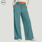 Front view of a woman wearing mint green wide-leg fleece-lined sweatpants with a drawstring elastic waistband and side pockets. The pants have a relaxed fit, perfect for casual wear or lounging, and are paired with a white long-sleeve crop top and white sneakers.