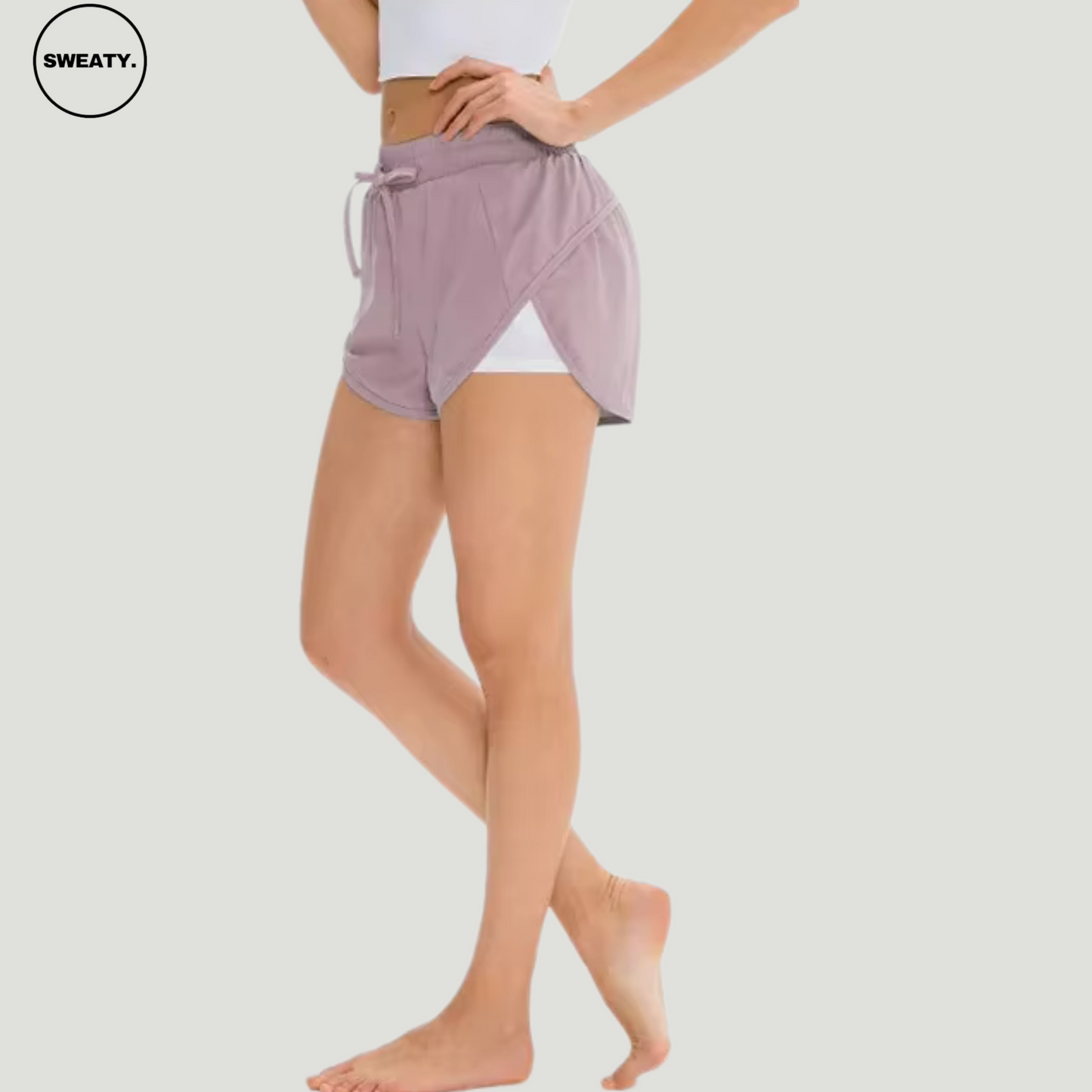 Side view of a woman wearing a pink 2-in-1 skort from SWEATY, highlighting the layered design with inner compression shorts and an adjustable drawstring waistband for a secure fit.