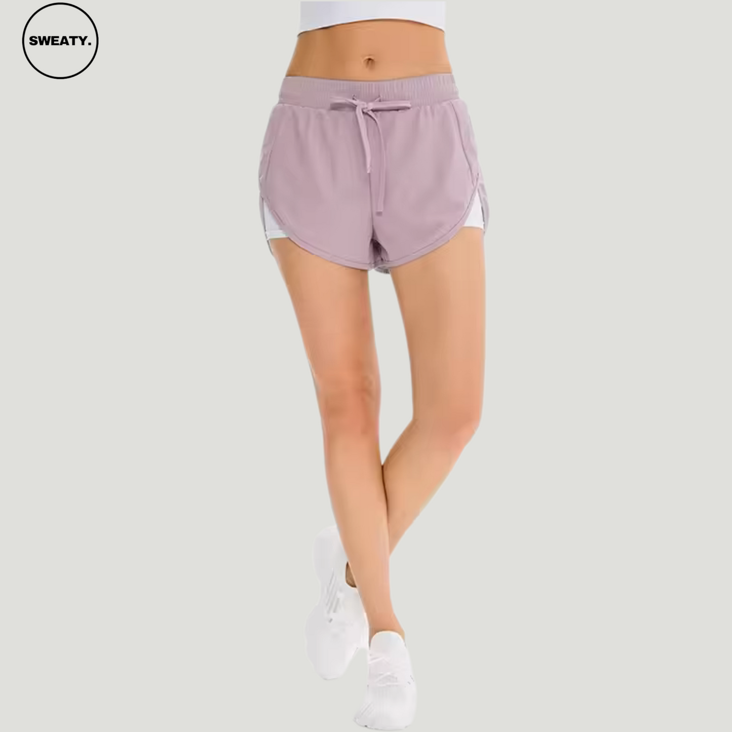 Front view of a woman wearing a pink 2-in-1 skort from SWEATY, designed with an adjustable drawstring waistband and inner compression shorts for enhanced comfort and flexibility.